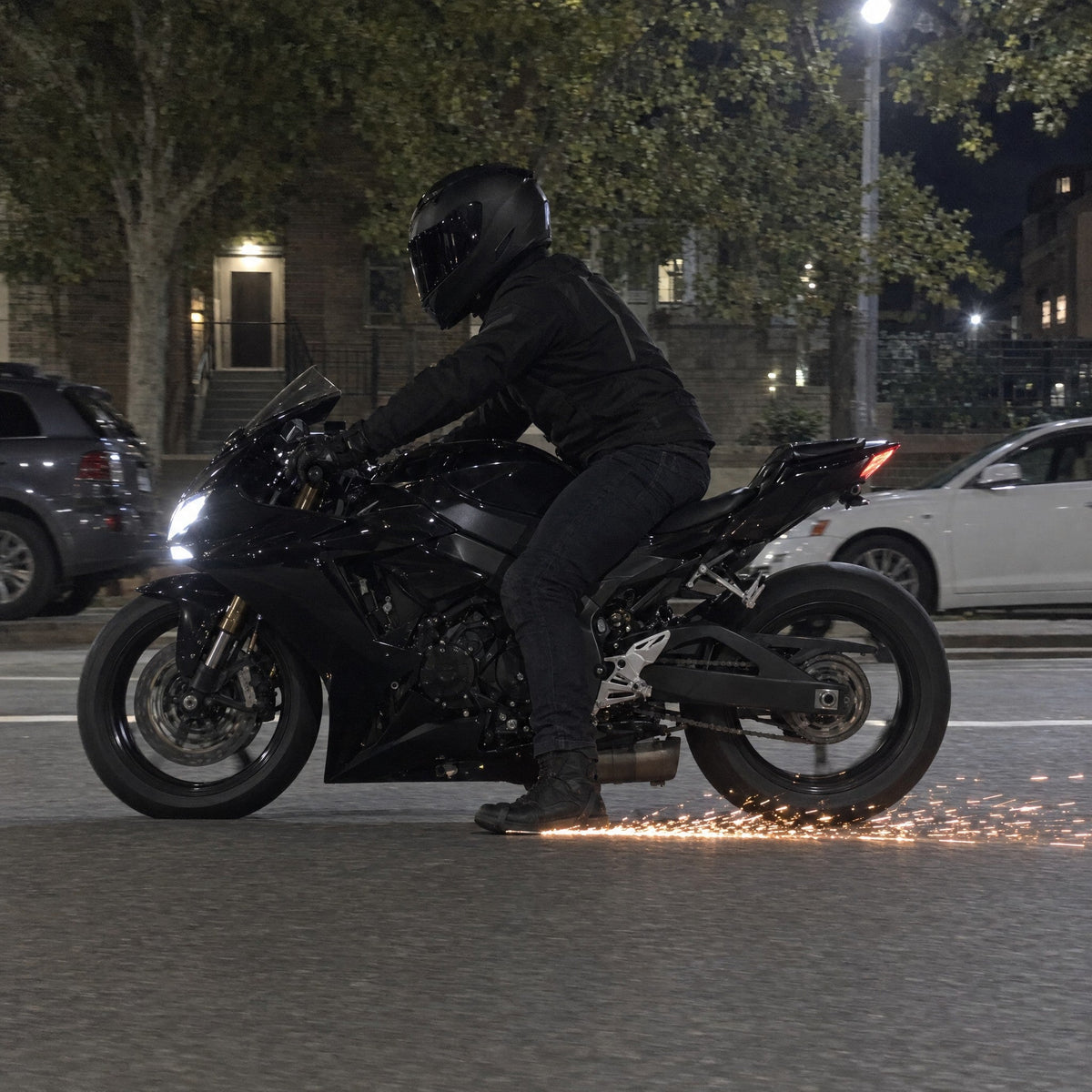 A rider on a city street with sparks trailing off his boot